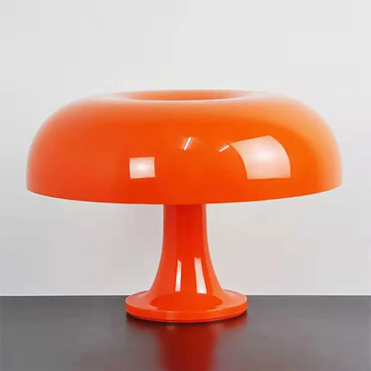 Glossy orange mushroom table lamp placed on a black surface against a neutral background