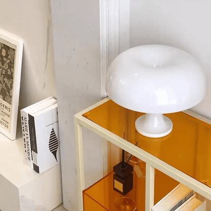Unlit white mushroom lamp placed on a modern orange shelf beside books and decorative items